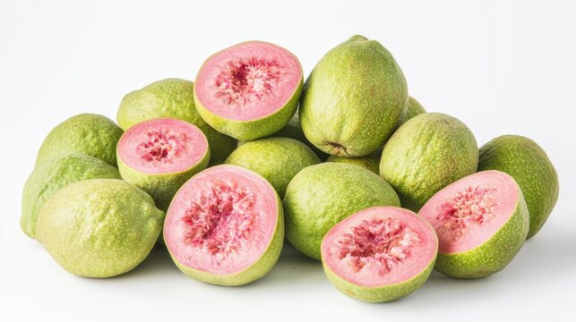 Guavas, some sliced to reveal their bright pink interiors, isolated on a white background