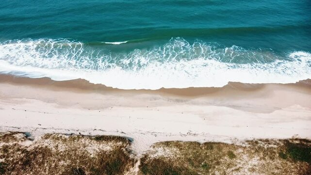 Vista a&eacute;rea de drone voando sobre uma bela praia no Brasil com vista para as ondas do oceano e &aacute;gua batendo na praia de areia do &acirc;ngulo aberto