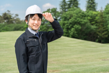 公園管理をする作業服姿の若いアジア人男性作業員（造園業・庭師・園芸・公務員）
