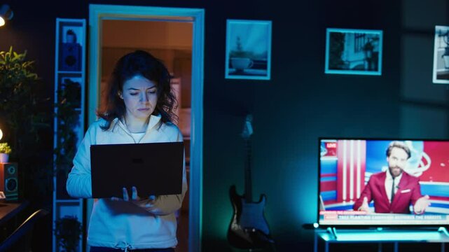 Computer scientist walking at home, developing software applications using laptop. IT professional standing in living room, implementing and maintaining company systems, camera B