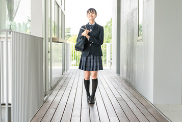 校舎の廊下を歩く制服姿の中学生・高校生の女の子
