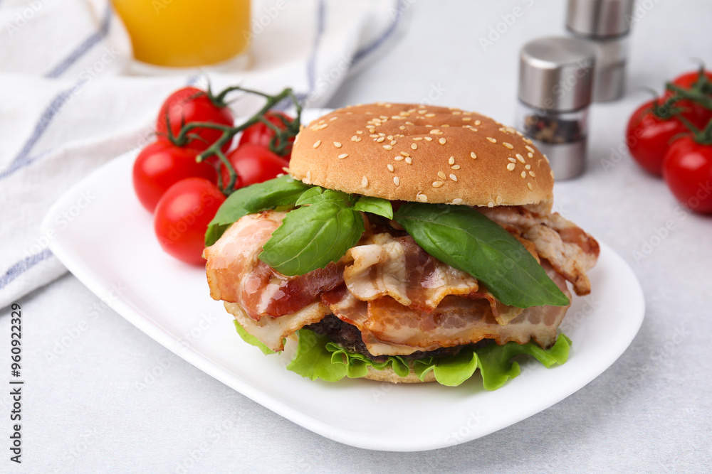 Poster Delicious burger with bacon, greens and tomatoes on light table