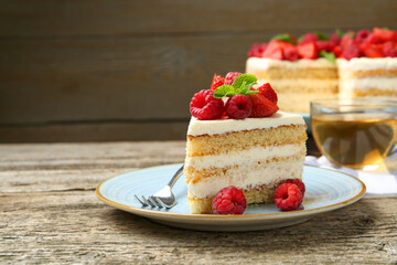 Piece of tasty sponge cake with fresh berries and mint served on wooden table