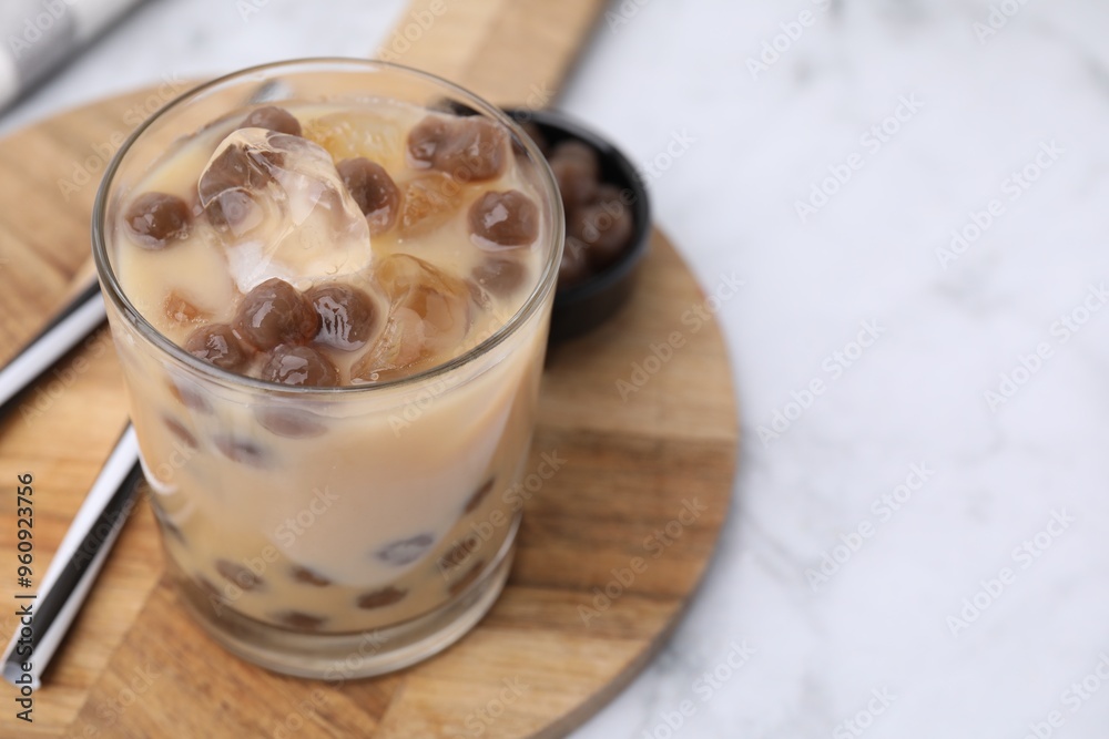 Sticker Tasty milk bubble tea in glass, tapioca pearls and straws on white marble table, closeup. Space for text