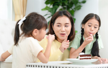 Happy young mother with daughter relaxing together in living room, Asian mom enjoying with child at home