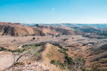 scenic winding road in arid mountains, sunlit rocky terrain. Ideal for adventure, travel, and exploration.