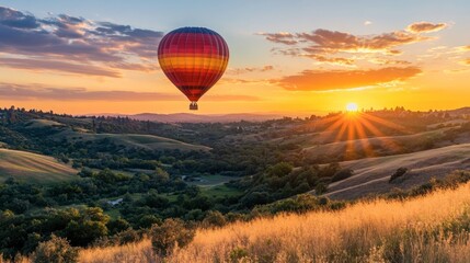 Obraz premium A hot air balloon flying over rolling hills at dawn, with the sun rising in the background.
