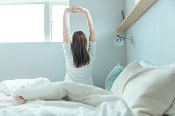 ベットから起き上がる女性の後ろ姿　wake up
