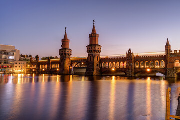 Fototapeta premium The Oberbaumbruecke over the river Spree in Berlin at twilight with a motion blurred subway