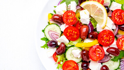 Greek salad with white cheese, olives, tomatoes, paprika, cucumber and onion. White background, top view