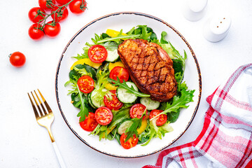 Tasty salad with grilled duck breast with vegetables and lettuce on white background, top view