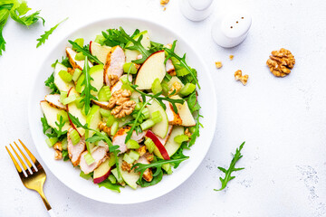 Old fashioned salad with chicken, red and green apples, raw celery, lettuce and walnuts, white background, top view
