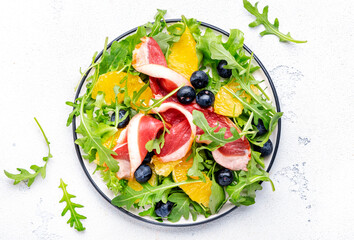 Tasty salad with grilled duck and juicy orange, blueberry and arugula on white background, top view