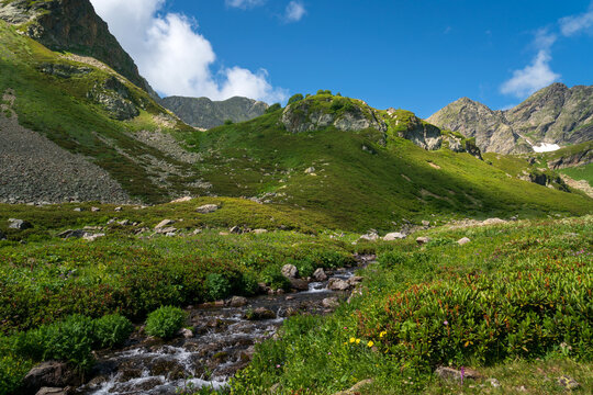 The valley of the Malaya Dukka River on the slopes of the Arkasar ridge in the North Caucasus and the tourist trail to the Dukka Lakes on a sunny summer day, Arkhyz, Karachay-Cherkessia, Russia