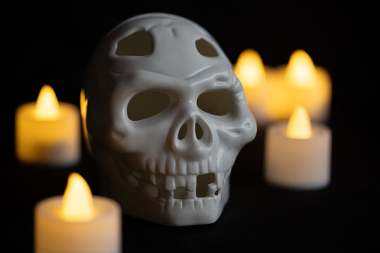 cr&aacute;neo cadav&eacute;rico de pl&aacute;stico blanco iluminado por luz de veladoras artificiales