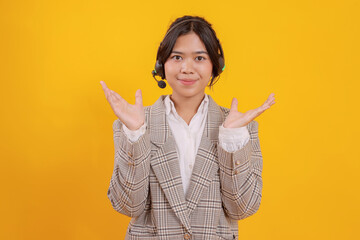 Young Asian Woman Shrugging Hands as a Customer Service Call Center Isolated On Yellow Background