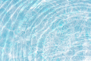 Obraz premium Blue water with ripples on the surface. Defocus blurred transparent blue colored clear calm water surface texture with splashes and bubbles. Water waves with shining pattern texture background.