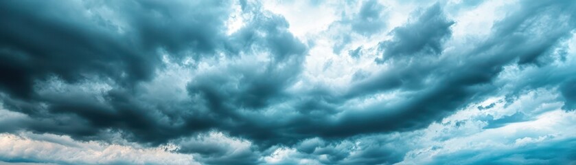 Obraz premium Dramatic clouds fill the sky with deep shades of blue, creating an atmospheric and moody backdrop for various projects.