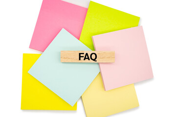 FAQ wooden block on colorful sticky note. FAQ is frequently asked questions.