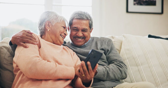 Senior couple, phone and happy on sofa with hug, reading and notification with funny story in home. Woman, man and smartphone in retirement, relax and embrace with comic memory on mobile app in house