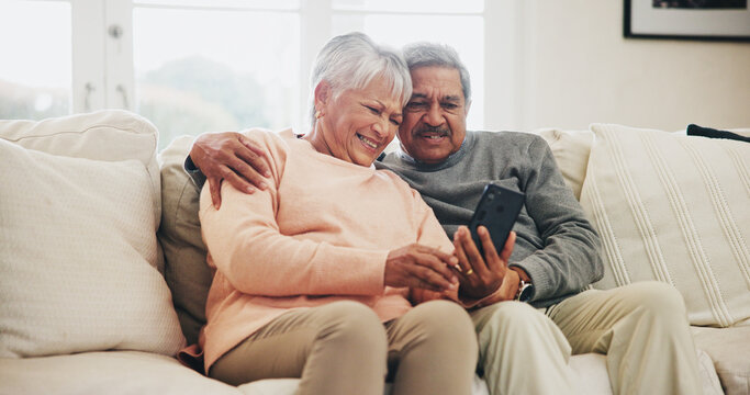 Senior couple, smartphone and happy on sofa with hug, reading and notification with funny story in home. Woman, man and phone in retirement, relax and embrace with comic memory on mobile app in house