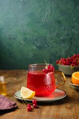 Hot drink, tea with viburnum and citrus in a transparent glass mug on a wooden background. Autumn...