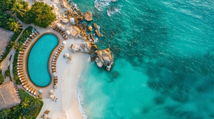 Fototapeta premium High-angle of the white house with a pool on top of the blue sea with little rocks