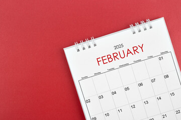 February 2025 desk calendar on red background.