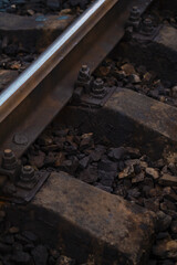 Close-up view of weathered railway tracks with rusted bolts and gravel during golden hour light