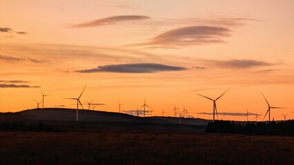Wind turbines on wind farm under beautiful orange sunset sky at Galway, Ireland, green energy, environment, nature background