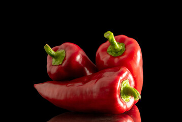 Three sweet red peppers, macro, isolated on black background.