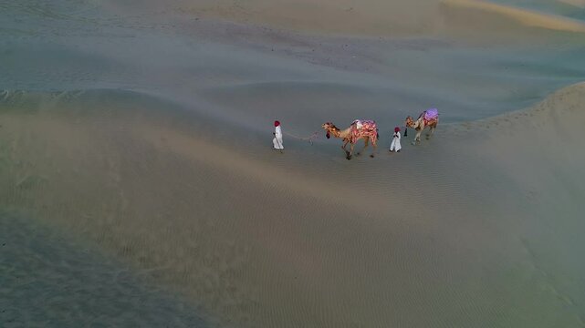 Indian People walking with camels on sand dunes at thar desert, Jaisalmer Rajastha, India. 