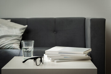 Eyeglasses with stack of books, and the glass of water on the table