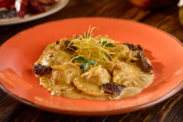 Gourmet Mushroom Ravioli in Cream Sauce with Morel Mushrooms on Wooden Table