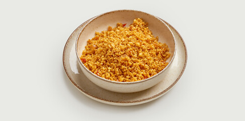 A bowl of golden-brown couscous is presented on a beige plate against a clean white background. The couscous is cooked to perfection
