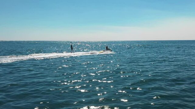 Jet ski's towing athletes hydro foiling on the ocean aerial view on bright summer's day in Sydney, Australia