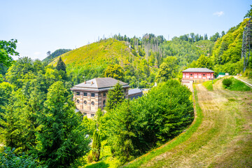 The Spalov Hydroelectric Power Plant is surrounded by lush greenery and rolling hills in Czechia, showcasing its integration into the natural landscape