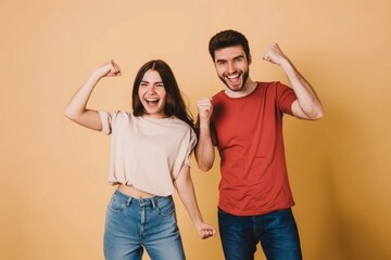 Fototapeta premium Two joyful friends celebrating together in casual outfits against a light beige background, capturing a moment of happiness and connection