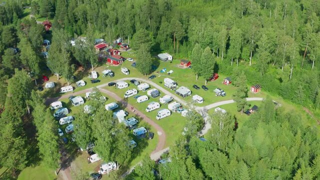 Camping ground in nature and forest. Aerial drone view of caravan motorhome campsite in beautiful evening light. Surrounded by nature and green woods in clean environment.