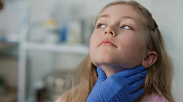 Closeup pediatrician checking throat after disease. Cute blond girl open mouth