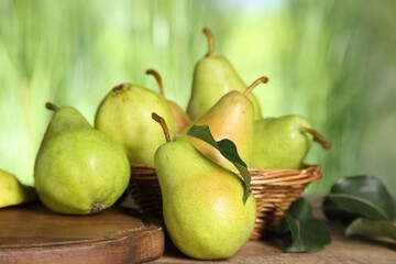 Fresh pears and leaves on wooden table against blurred green background, closeup