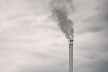 Smokestack with emissions under overcast sky