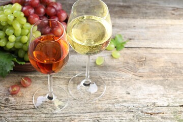 Fresh ripe grapes and glasses of wine on wooden table, closeup
