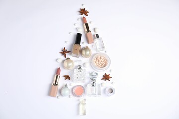 Christmas tree shape made of perfume bottles and cosmetic products on white background, flat lay