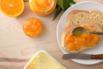 Macro of orange jam jar on bread and containers