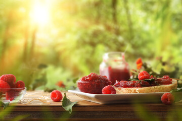 Homemade raspberry jam on wooden table and nature background