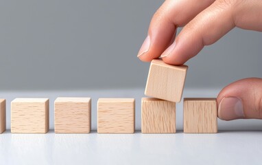 Businessperson arranging wooden blocks in a line, symbolizing strategy, growth, and careful planning in business operations