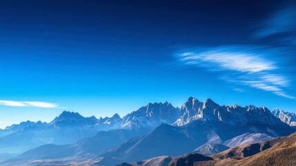 Obraz premium A clear sky over a mountain range, with peaks sharply defined against the bright blue background.