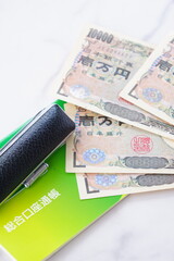 テーブルの上に置かれた銀行の預金通帳と印鑑、1万円札
