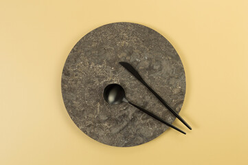 Top view of brown marble plate, black cutlery on yellow background. Food presentation, stone tray. Copy space, flat lay.